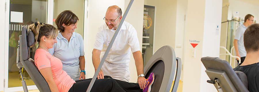 Der Chefarzt der Rehaklinik Sonnhalde hilft einer Patentin bei einer Übung an einem Fitnessgerät.